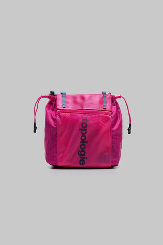 Small pink tote bag with top drawstring cords, front slip pocket, “topologie” logo