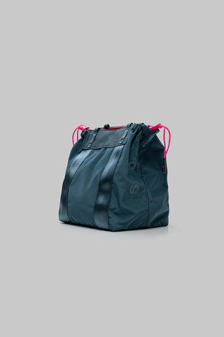 Small teal tote bag with drawstring cords and stitched front panel, angled view