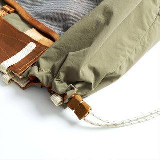 Folded tote corner with cord strap, gold leather patch, and stitched interior pocket.
