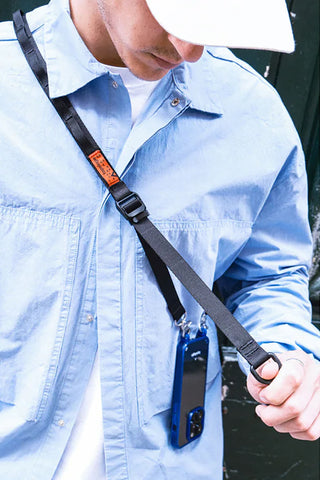 Black sling strap with adjustable buckle and pouch holding a device