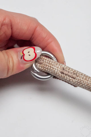 Hand holding flash grey 10mm rope loop strap with silver carabiner