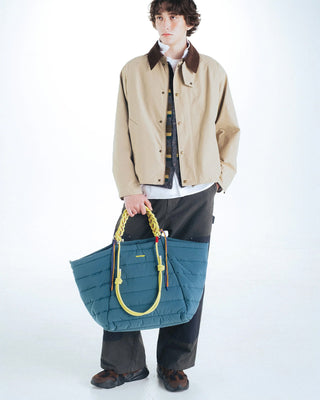 Neon lime braided O-rope strap on a blue crossbody bag, held at side