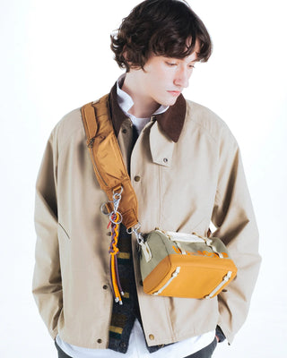 Orange braided keychain with metal clips and tag on tan jacket pocket
