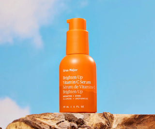 Ursa Major Brighten Up Vitamin C Serum orange pump bottle on rocks