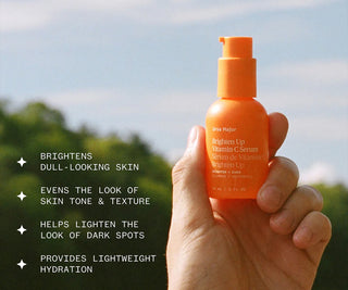 Orange vitamin C serum pump bottle held in hand