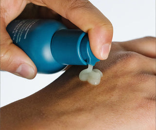 Serum drop dispensed from teal pump bottle onto forearm skin