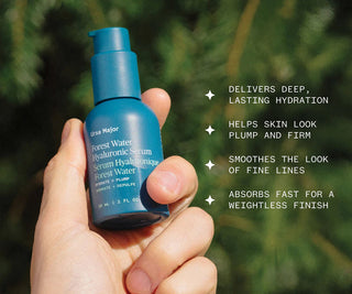 Hyaluronic serum bottle held in hand, showing teal pump and dark label