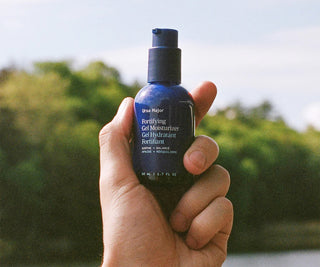 Ursa Major fortifying gel moisturizer bottle held in a hand, dark blue