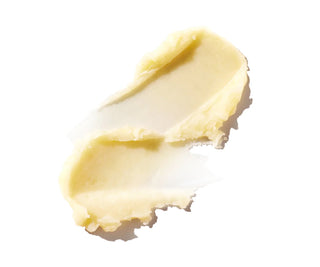 Pale yellow lip balm shown as a broken, scoop-like stick piece