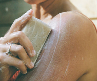 Fresh bar soap held in hands, pale cream with visible speckles