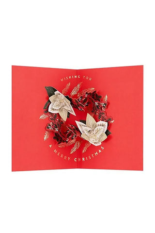 Folded red Christmas pop-up card with white poinsettia wreath and Merry Christmas text