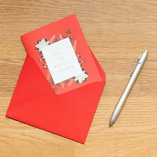 Red folded Christmas card with white floral pop-up and bow; next to a pen