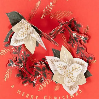 Red pop-up Christmas card with white poinsettia wreath, bows, and Merry Christmas text