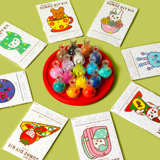 Sand art DIY kit: red tray with colorful sand bottles and instruction cards