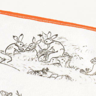 White cleaning cloth close-up with black animal scene and orange stitched edge.