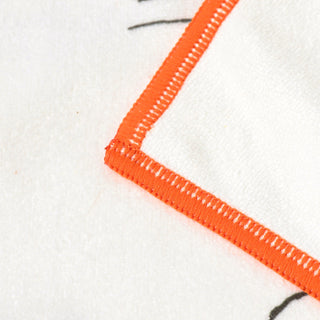 Corner of white cleaning cloth with orange hem stitching and black print detail.