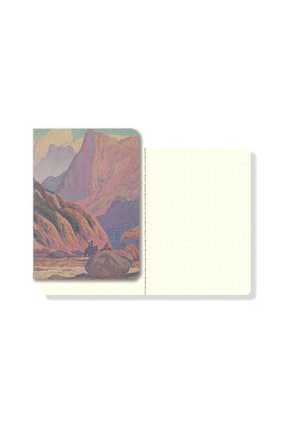 Pocket notebook open to cream blank pages, printed canyon landscape cover