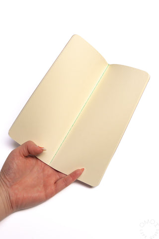 Topographical map notebook open, showing cream inner pages and stitched edge