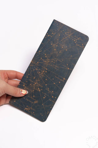 Dark navy star map notebook cover held in hand with gold constellation lines