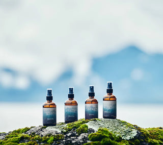 Botanical aroma mist bottles with black spray caps standing on rocky surface