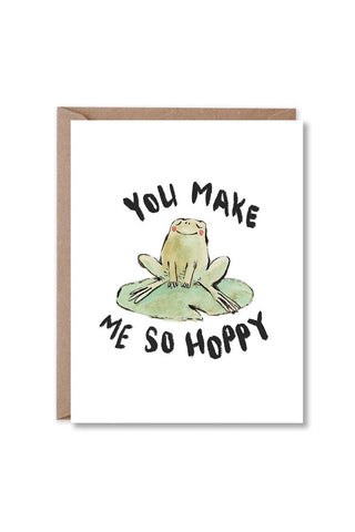 Greeting card front with green frog on lily pad and “You Make Me So Hoppy” message