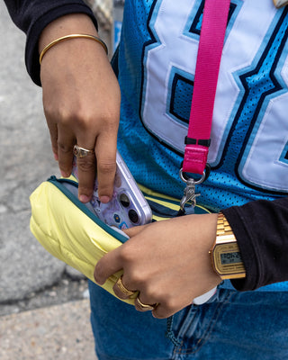 Canary yellow sling bag open at zip pocket with phone inserted