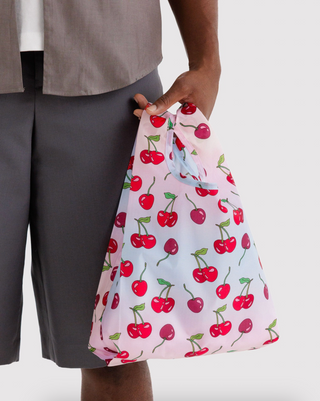 Baby BAGGU cherry print tote bag held by person, pink-white fabric with handles