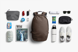 Brown daypack with accessories nearby, including bottle, shoes, and sunglasses
