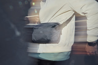 Dark gray mesh crossbody sling bag worn across chest on a person.