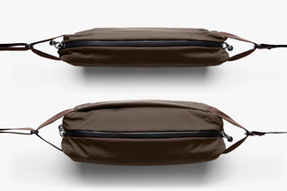 Brown sling bag shown front and back with top zipper and reinforced strap ends.