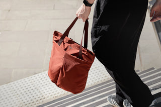 Orange Bellroy tote bag carried by a person using the top handles