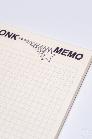 Close-up of beige grid memo pad edge with BONK MEMO title and star outline graphic