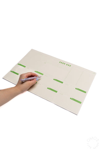 Two-week desk planner with green day blocks, open and being written on