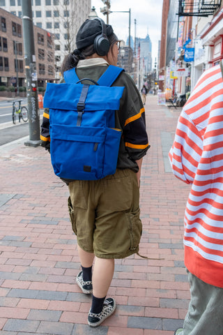 Bellroy indigo rolltop backpack worn outdoors with adjustable shoulder straps