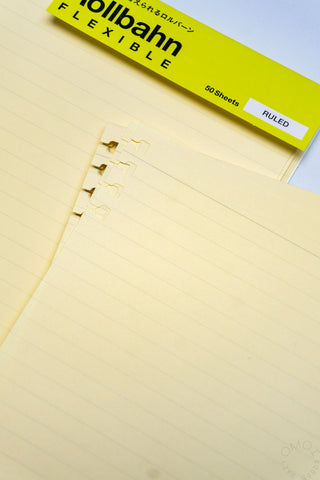 Cream ruled refill sheet close-up with perforation rings and soft line grid