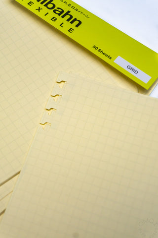 Cream grid refill sheet close-up with punched ring holes and edge tab