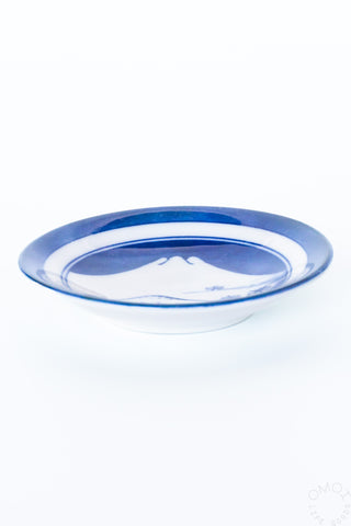 Side view of blue mini ceramic plate with white rim and mountain landscape