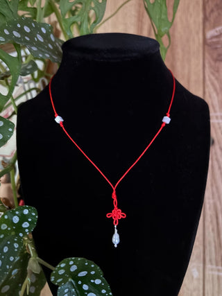 Lucky knot necklace with red cord, red clover pendant, and dangling pearl bead