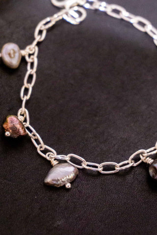 Petite silver-plated bracelet with dangling pearl-like and green bead charms on chain