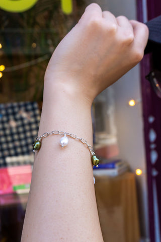 Silver-tone charm bracelet with pearl and green beads, worn on wrist