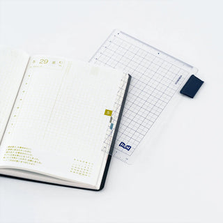 A5 pencil board with grid and Hobonichi HON branding, held by navy corner clip