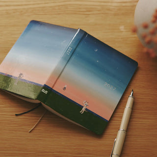 Hobonichi Techo A6 planner with blue gradient cover and illustrated figure, tied string