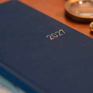 Close-up of navy planner cover with embossed “2027”