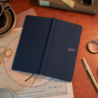 Opened dark blue 2027 planner showing weekly layout pages