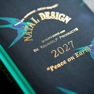 Close-up of 2027 planner cover text and teal bird illustration on dark background.