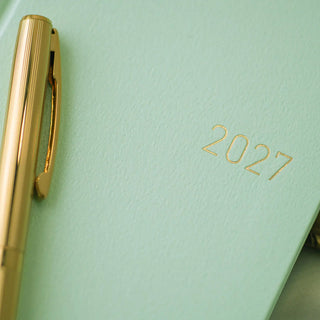 Close-up of jade green planner cover with gold “2027” on textured paper