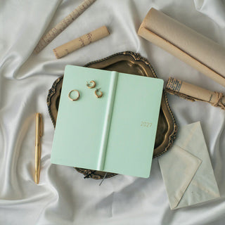 Jade green 2027 paper planner with black ribbon ties, closed cover and gold details