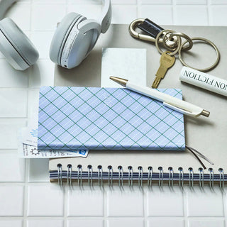 Plaid planner cover with elastic ties and gold pen accessories on a white page