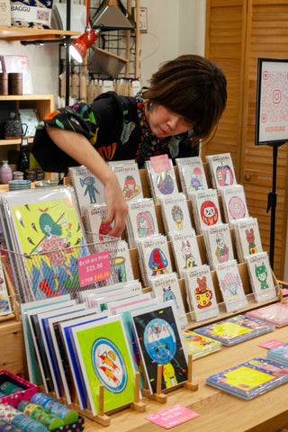 Child and instructor setting out art items on a workshop display table