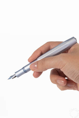Ice blue fountain pen held in hand, nib facing left